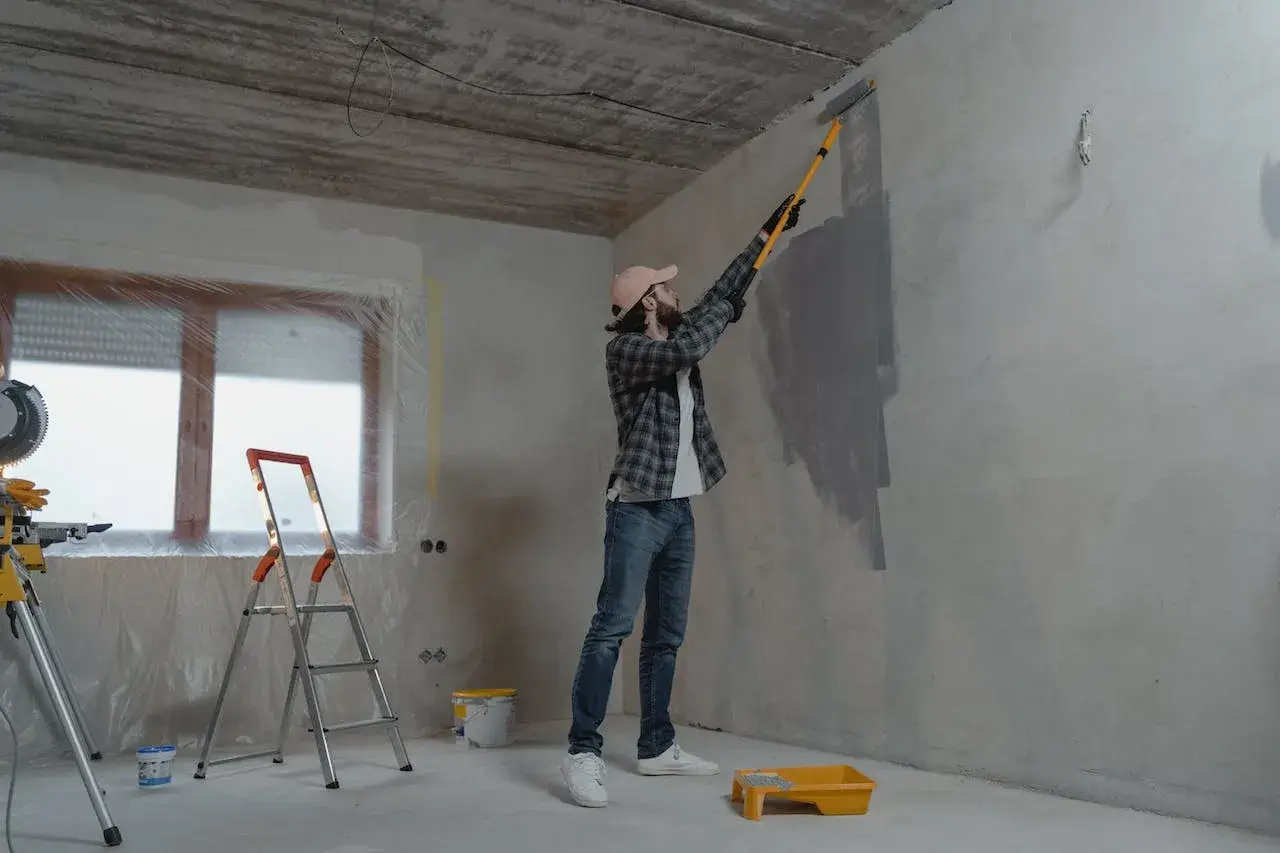 a man painting a wall in a room